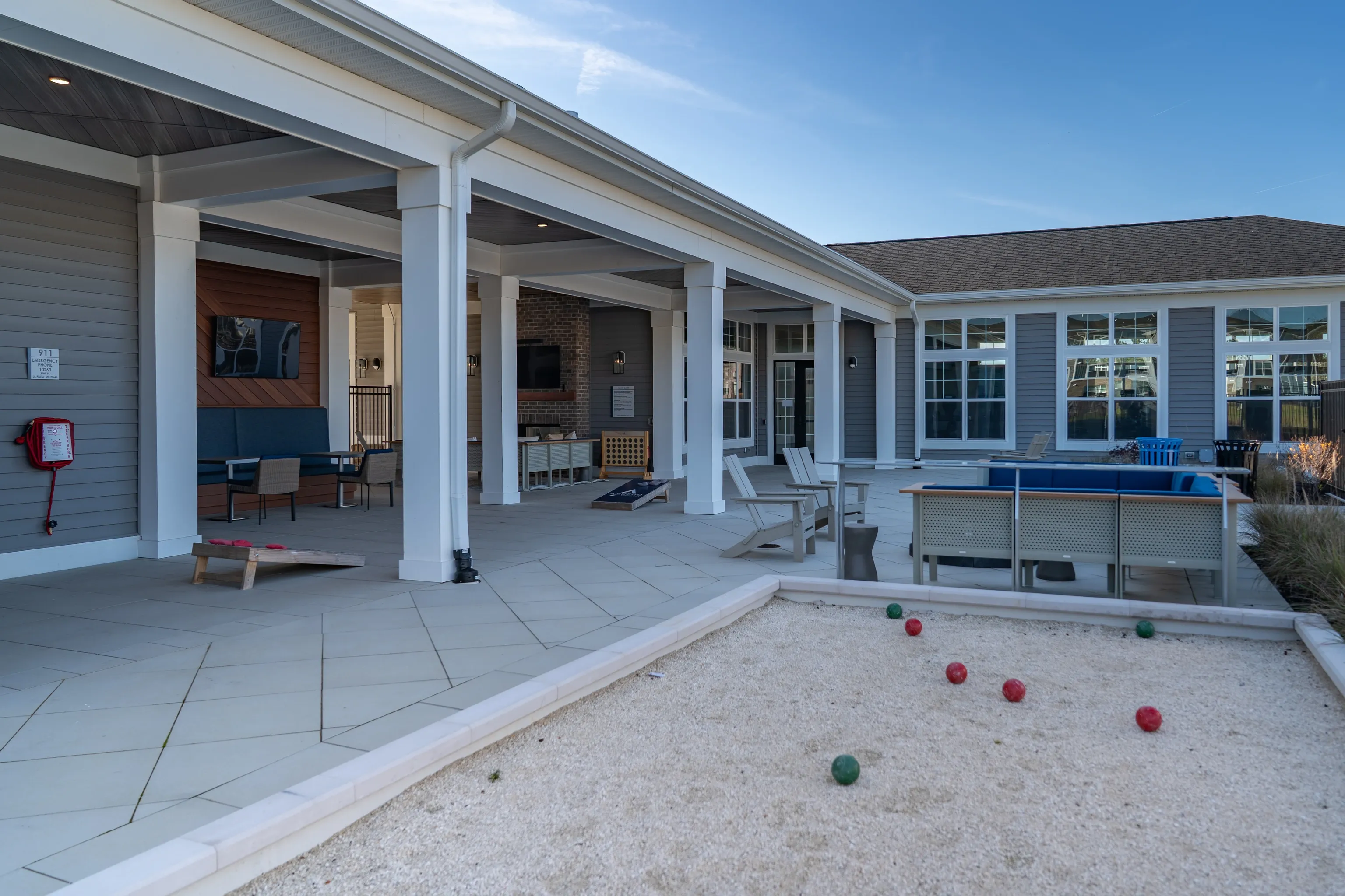 Covered patio area with seating, outdoor games, and bocce ball court.