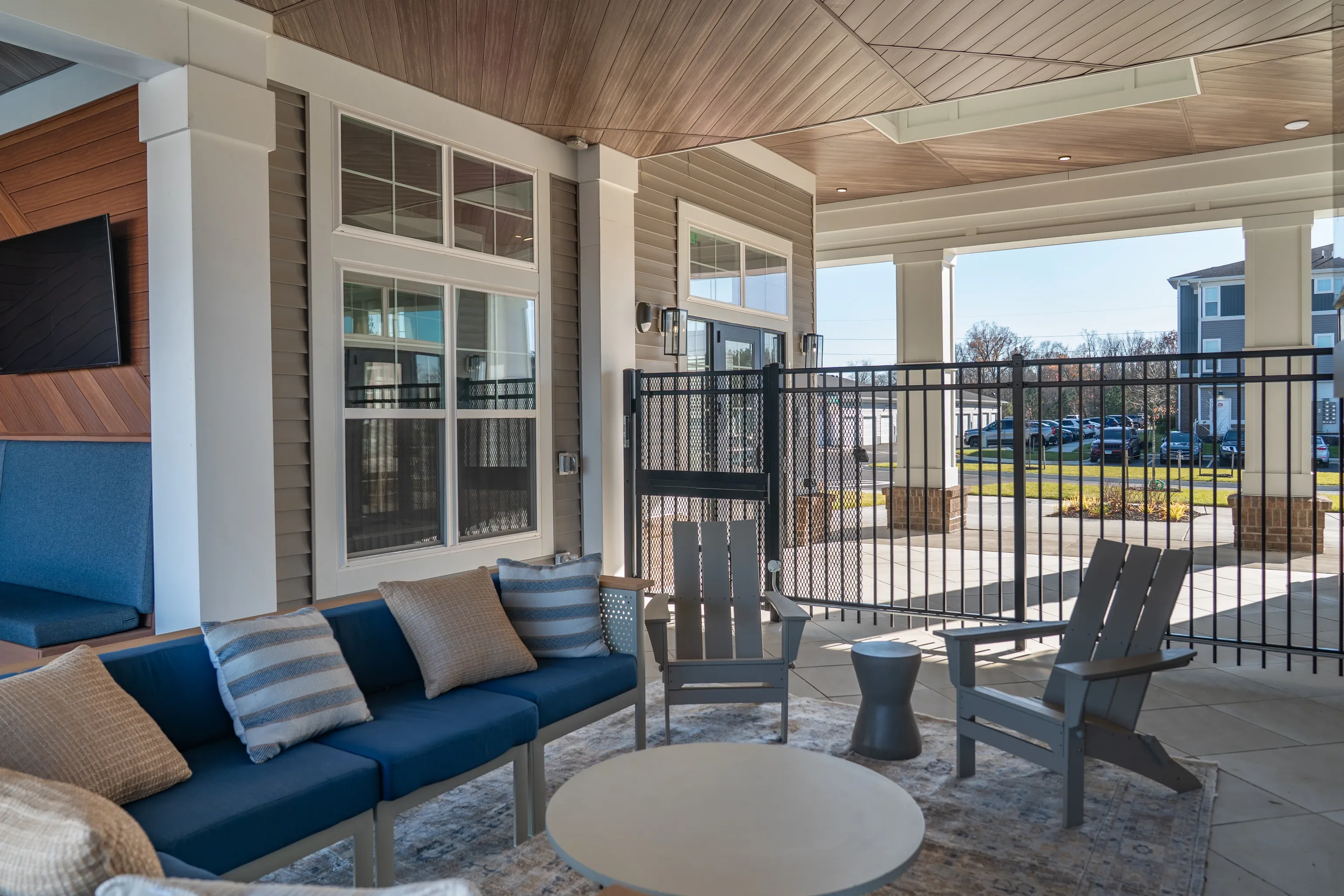 Covered outdoor patio with blue seating, chairs, and a round table.