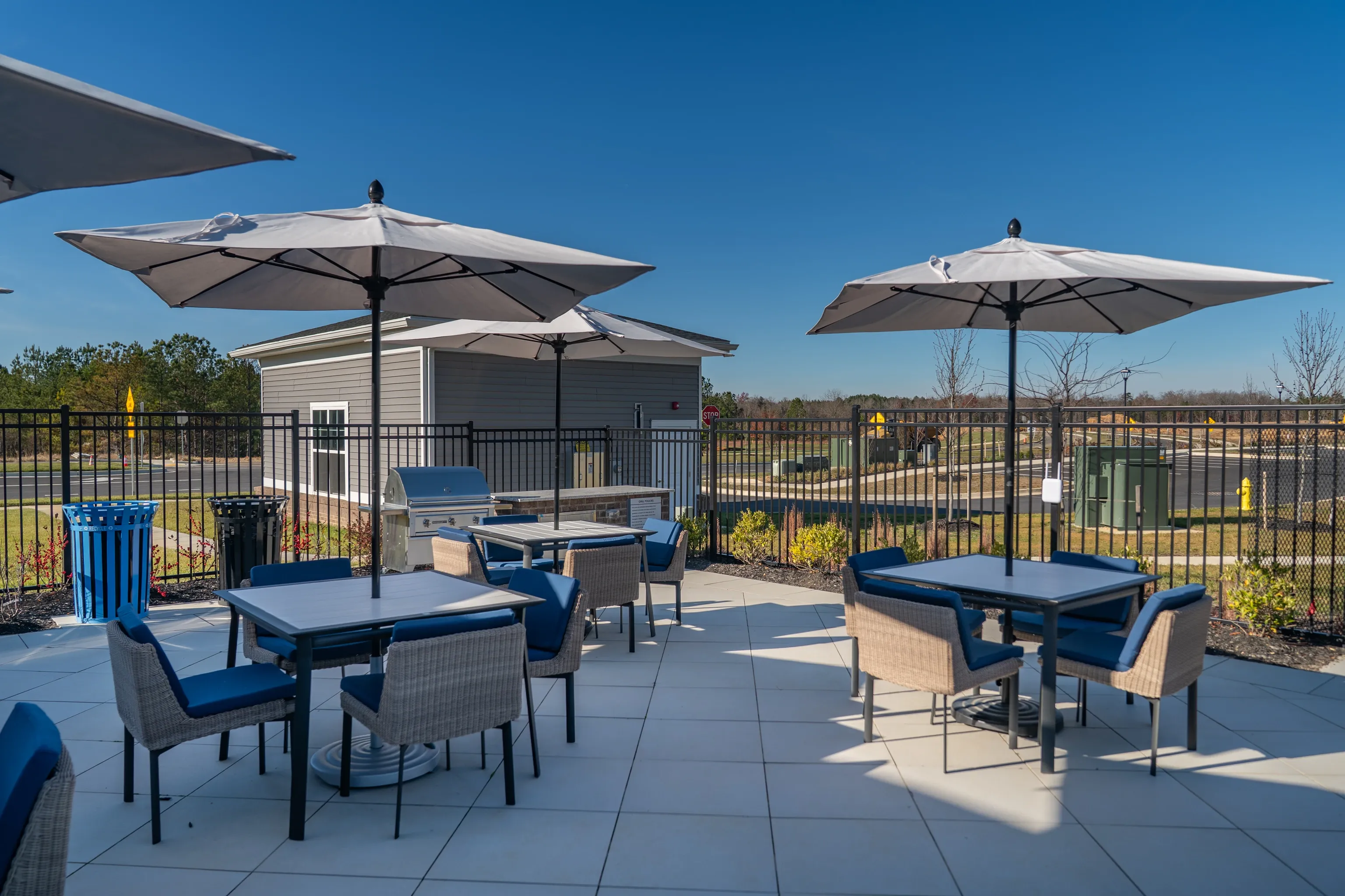 Outdoor seating area with tables, chairs, umbrellas, and grills.