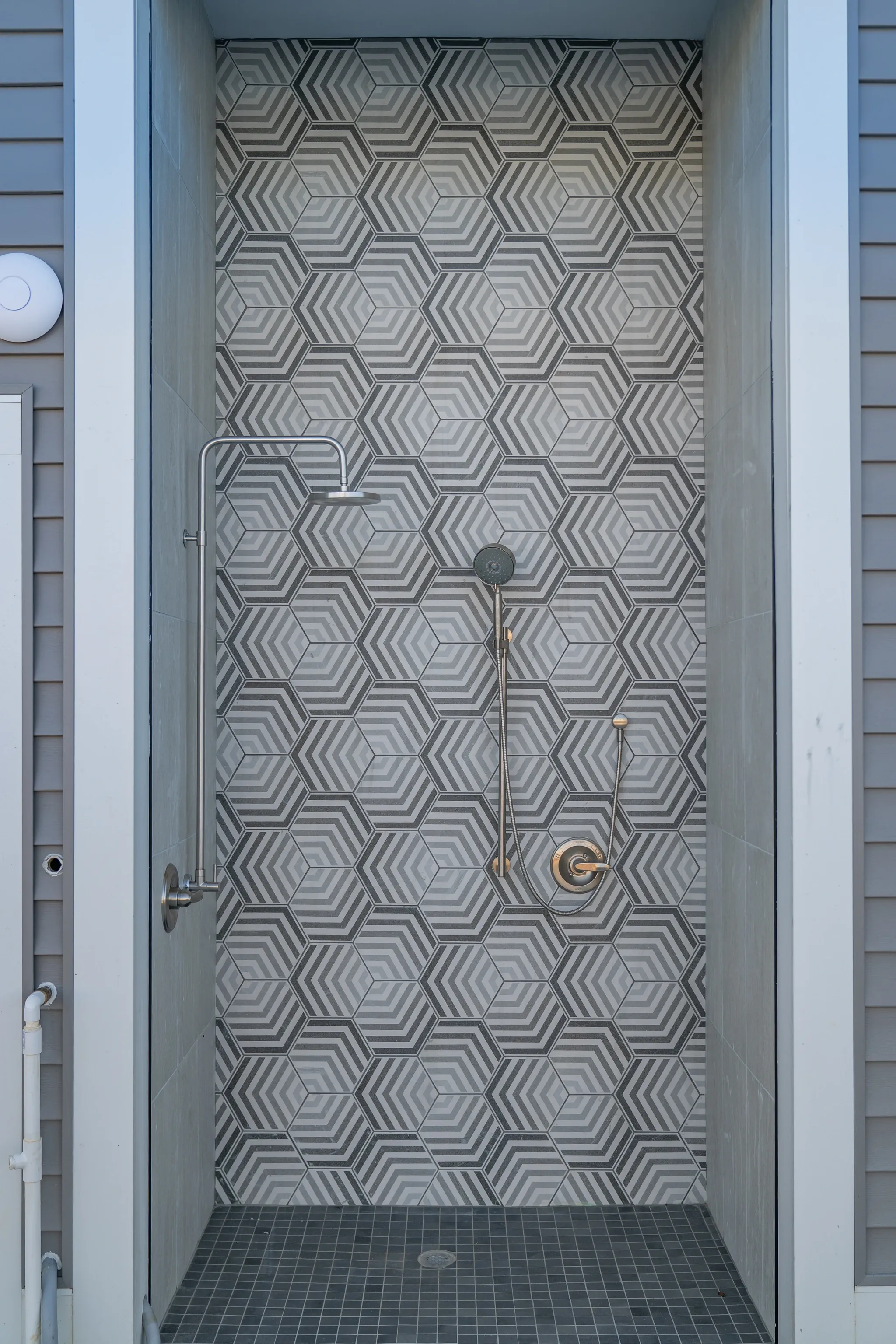 Outdoor shower with hexagonal tile accent wall and chrome fixtures