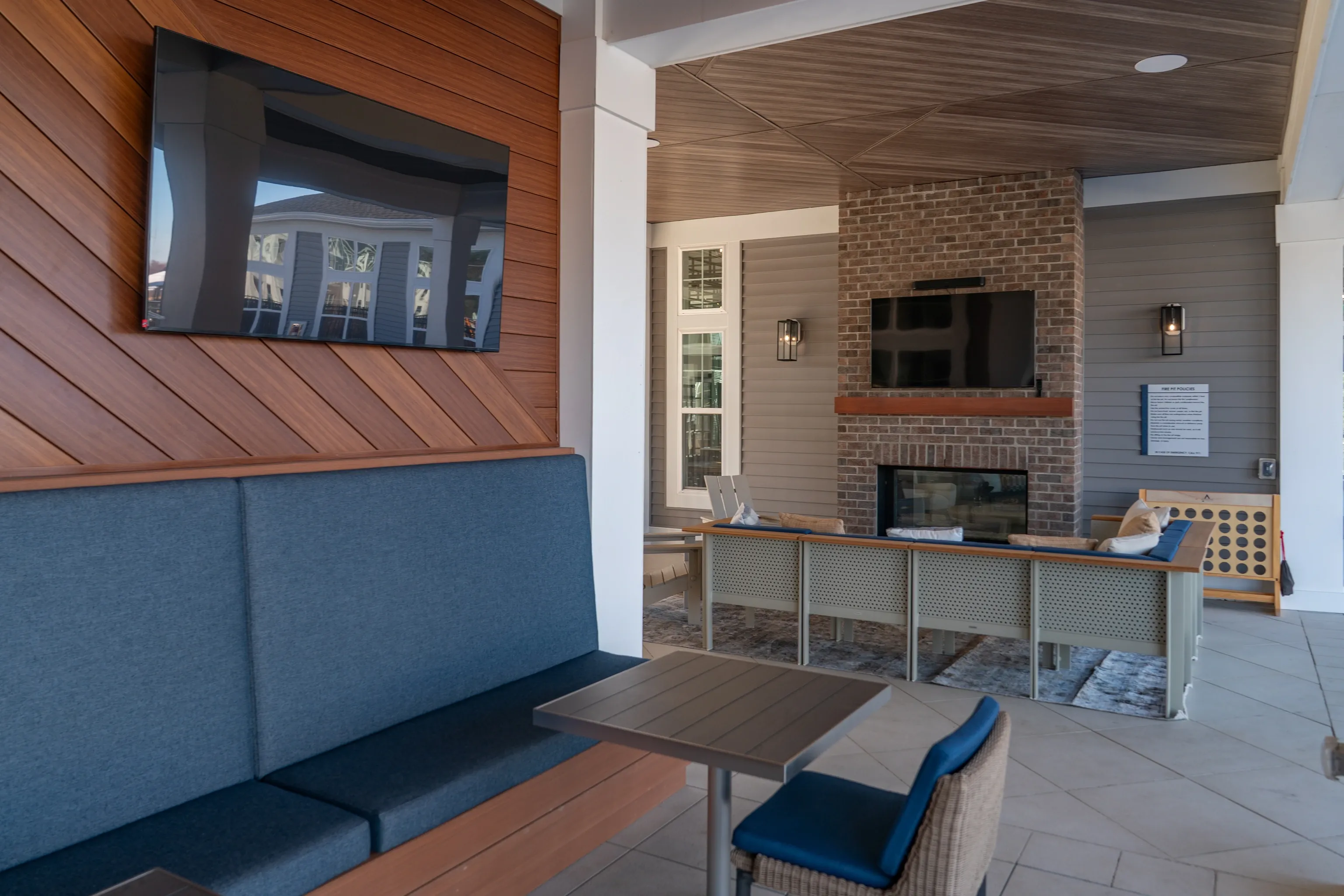 Outdoor lounge area with a TV, fireplace, and seating.