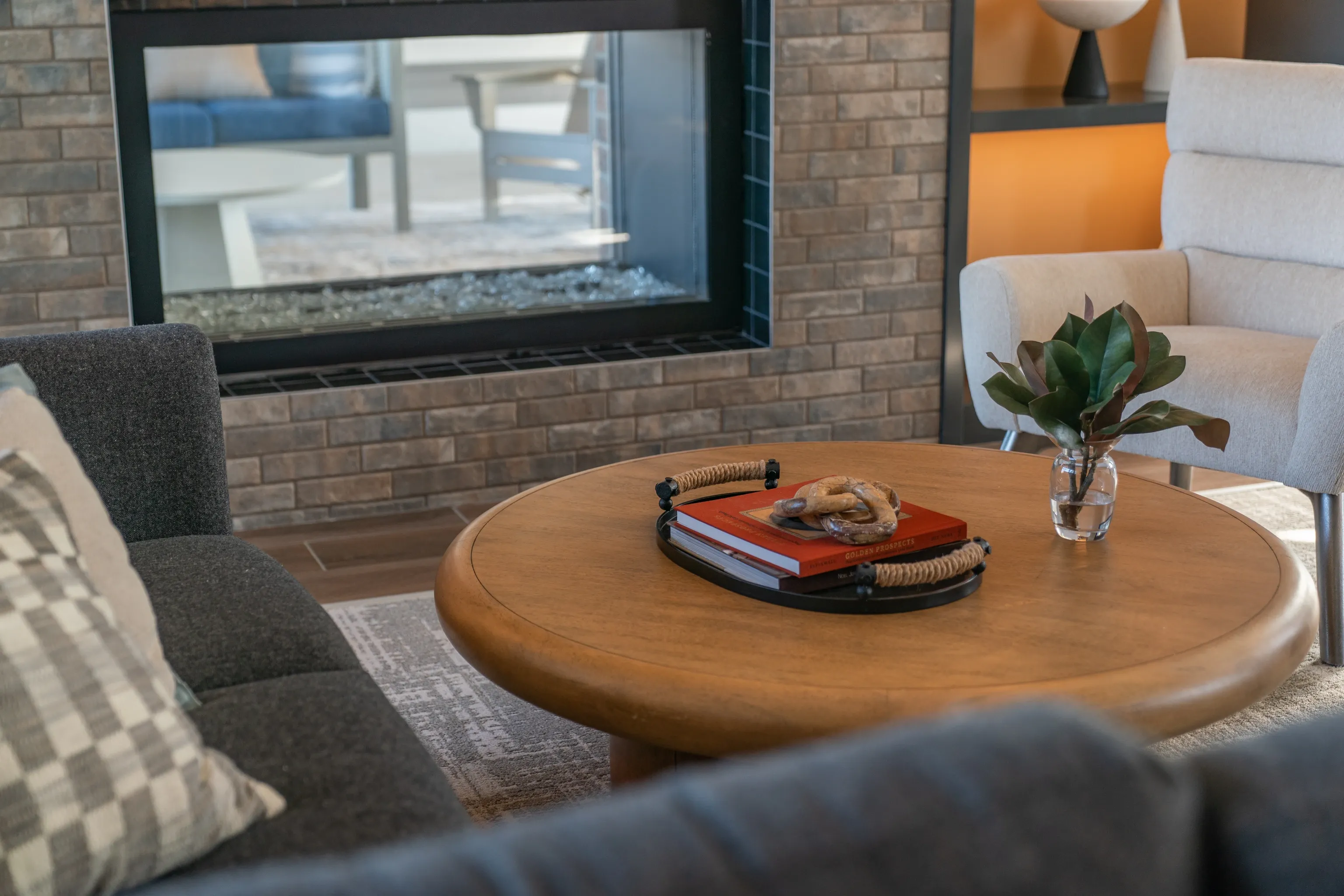 Living room with a fireplace, coffee table with books, and armchair.