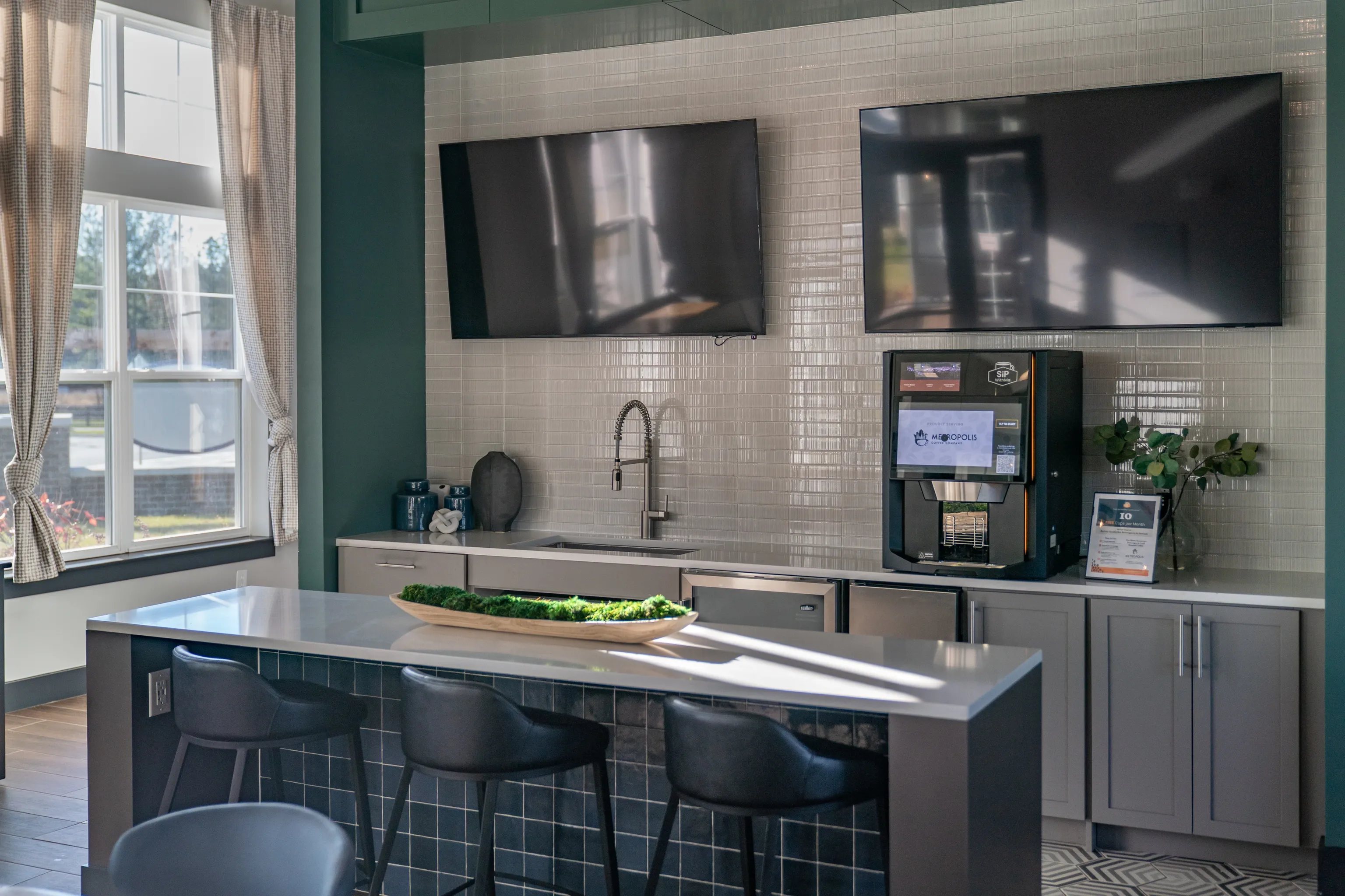 Modern community lounge with a coffee station, seating, and entertainment.