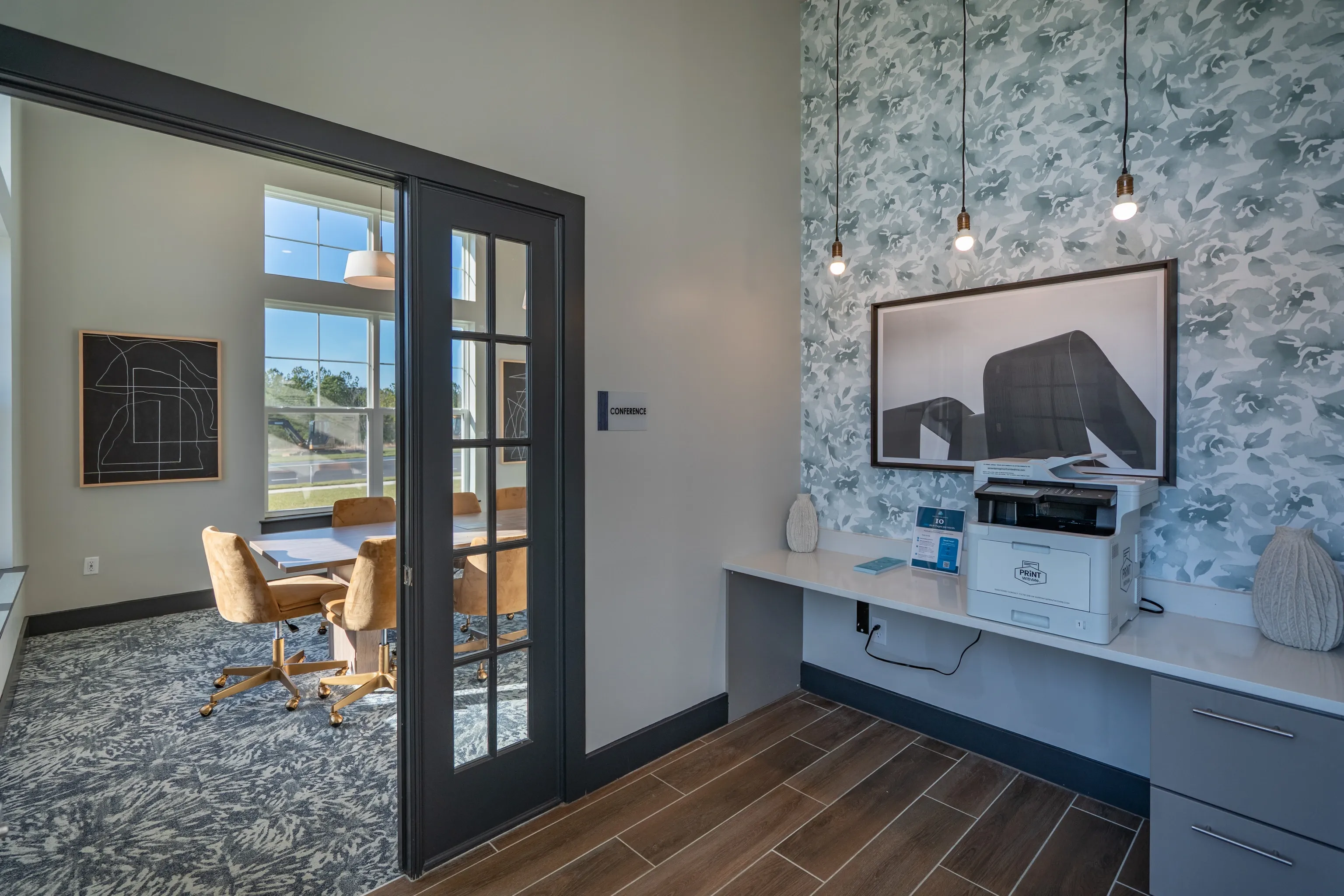 Conference room with a table and chairs and a business center with a printer and artwork.