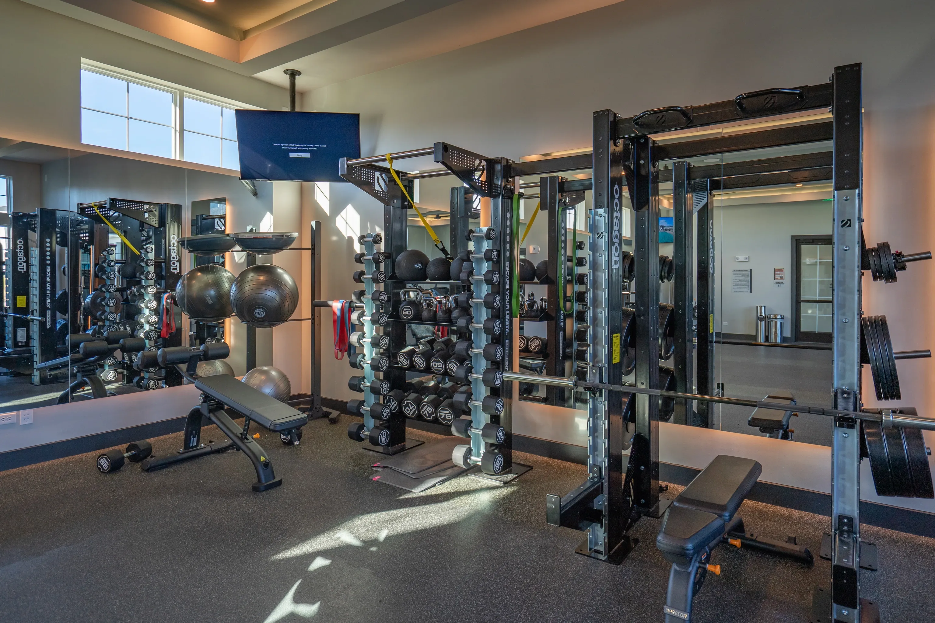 Weight room with dumbbells, barbells, weight benches, and workout machines.