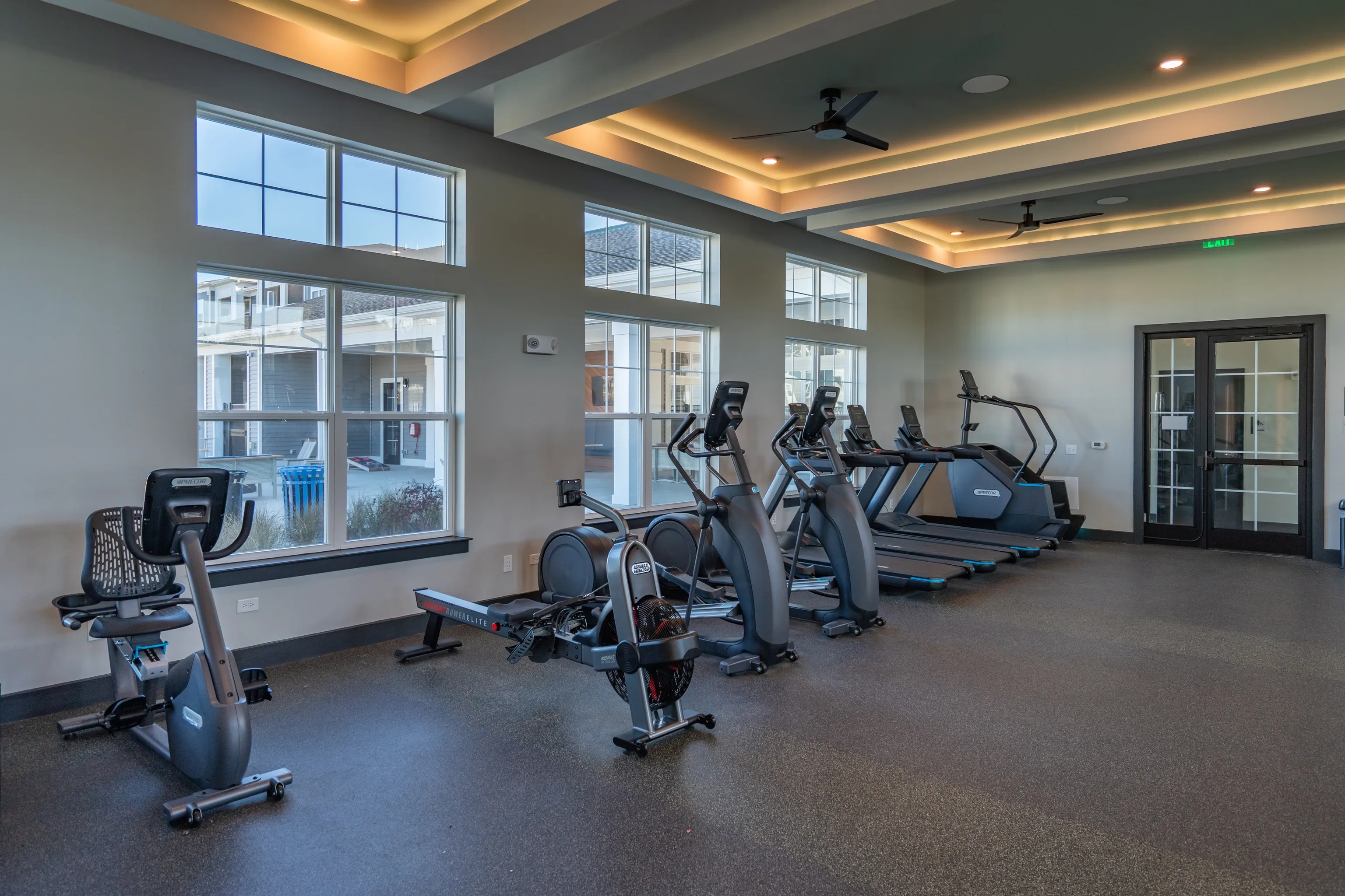 A well-equipped fitness center with treadmills, an elliptical, a rower, and a recumbent bike.