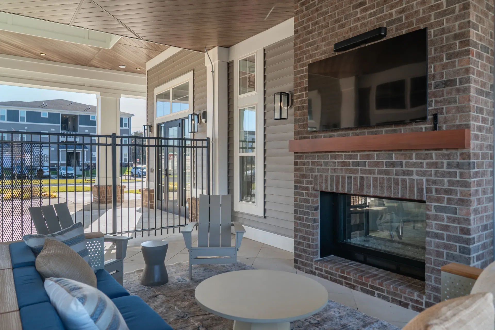 Covered outdoor lounge area with fireplace and TV.