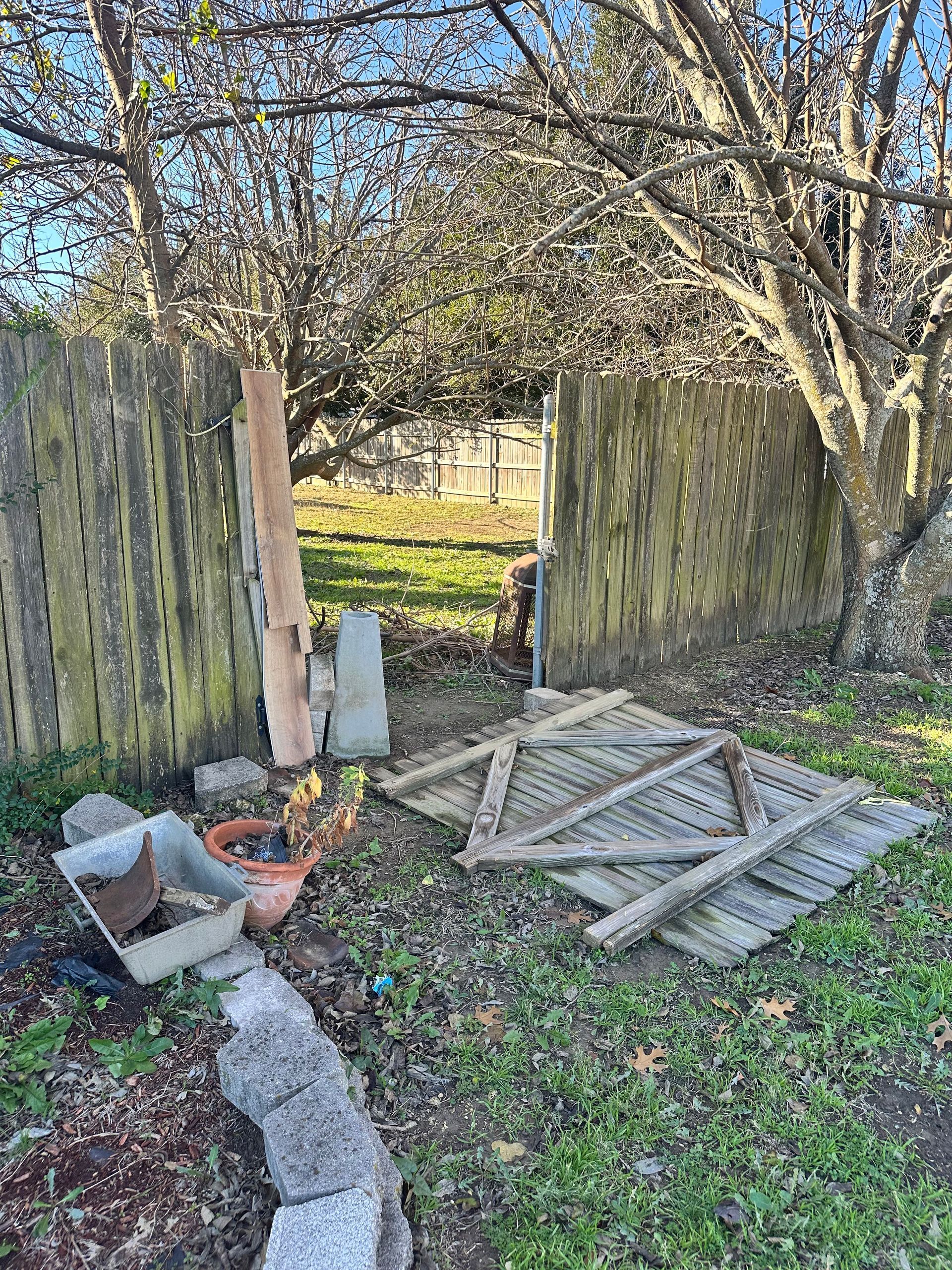 A wooden fence with a broken piece of wood in front of it.