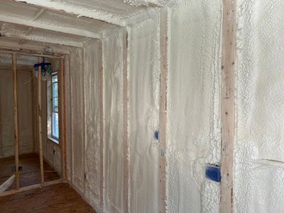 A man is spraying foam insulation on a wall.