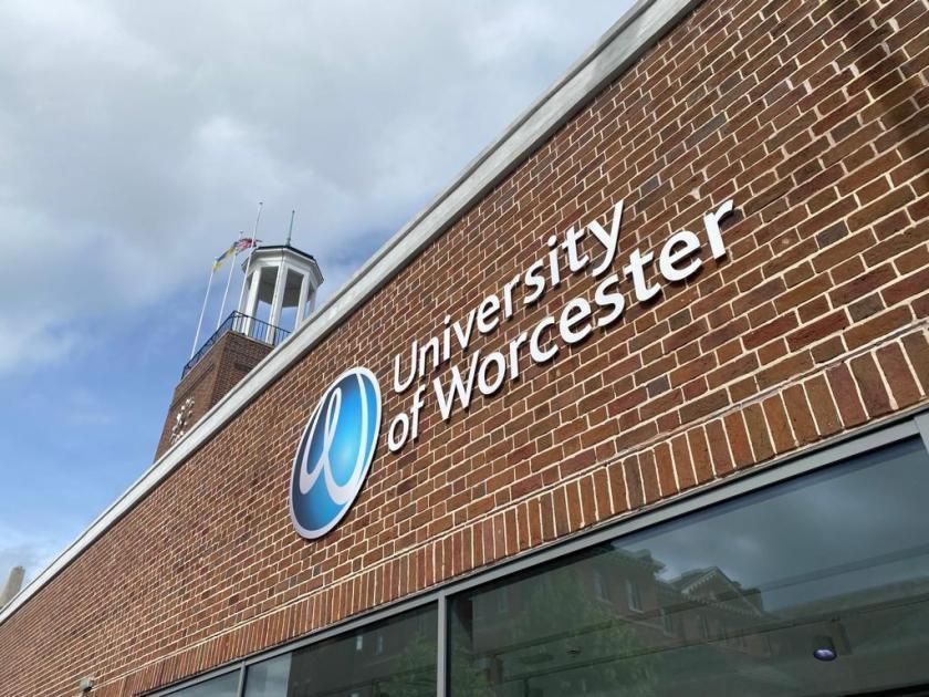 University of Worcester brick building with logo and sign against a cloudy sky