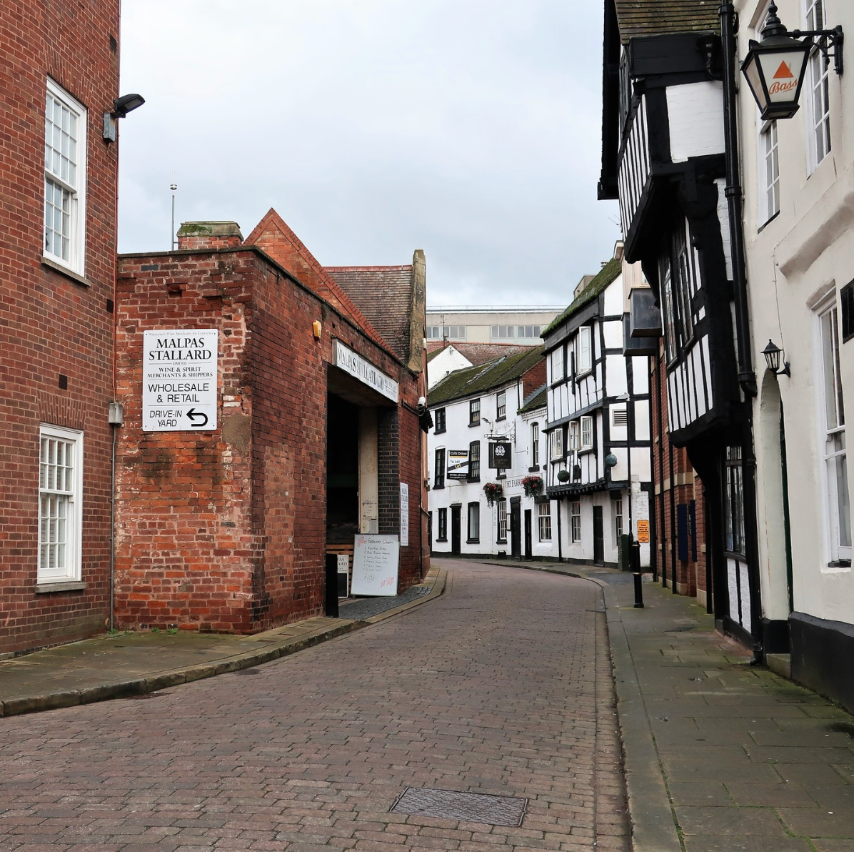 Narrow cobblestone street lined with red brick and white timbered buildings in a historic town center