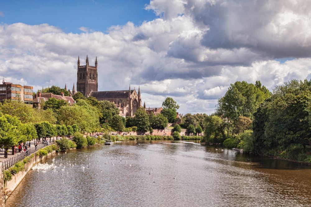 River with lush banks and a cathedral under cloudy skies in a townscape