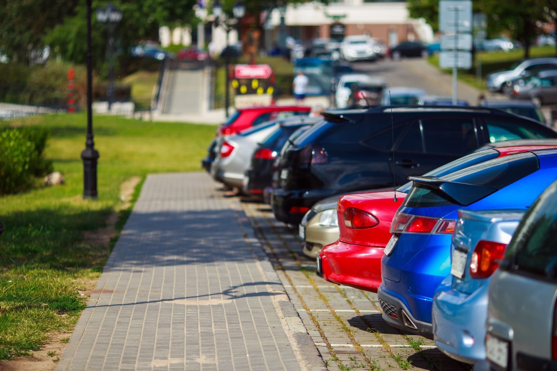 Row of parked cars beside a sidewalk on a sunny street