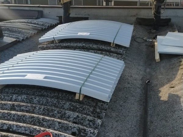 Pannelli lucernari in metallo curvo su un tetto di ghiaia sotto la luce intensa del sole