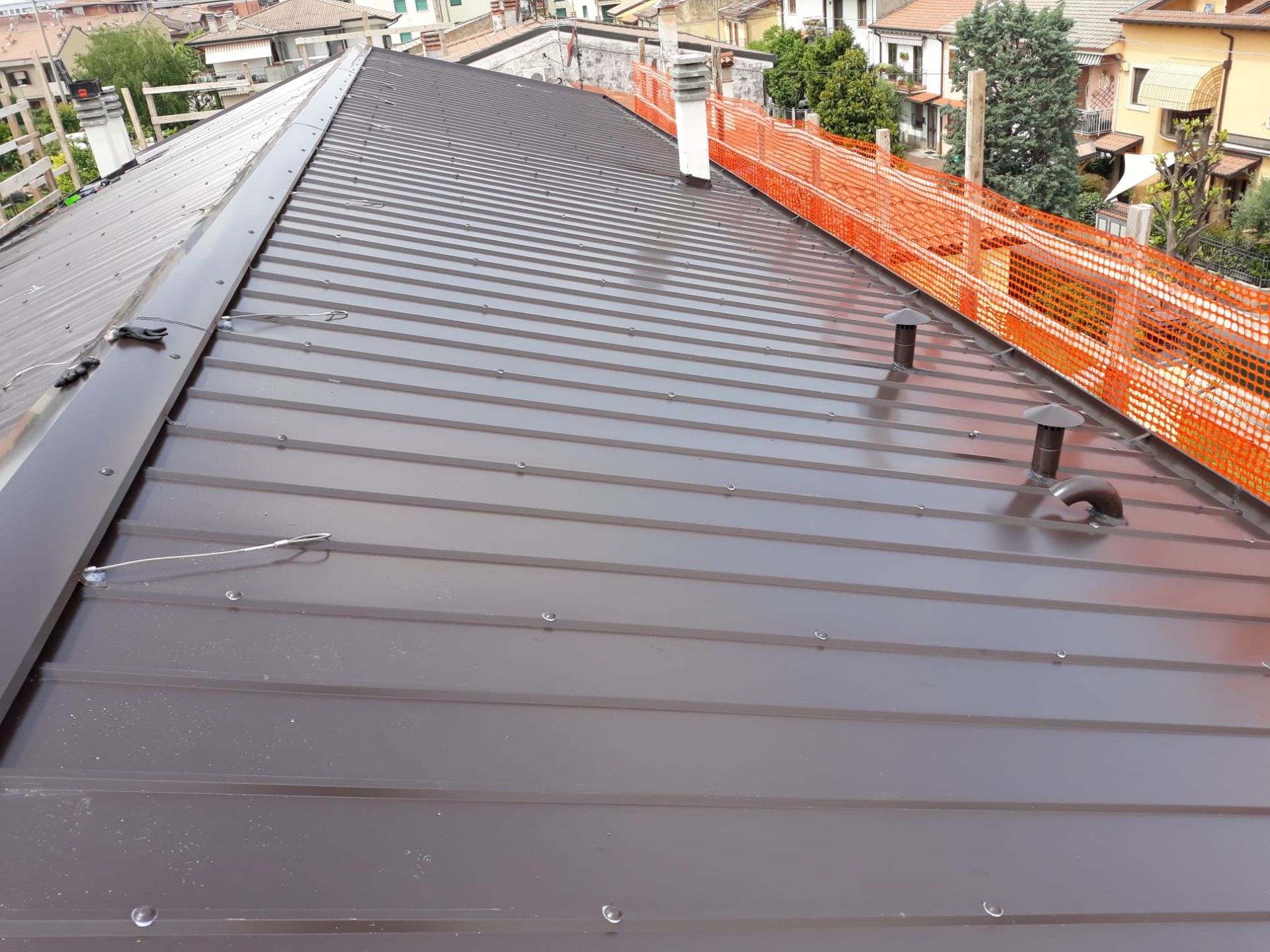 Tetto in metallo nero in costruzione con recinzione di sicurezza arancione lungo il perimetro