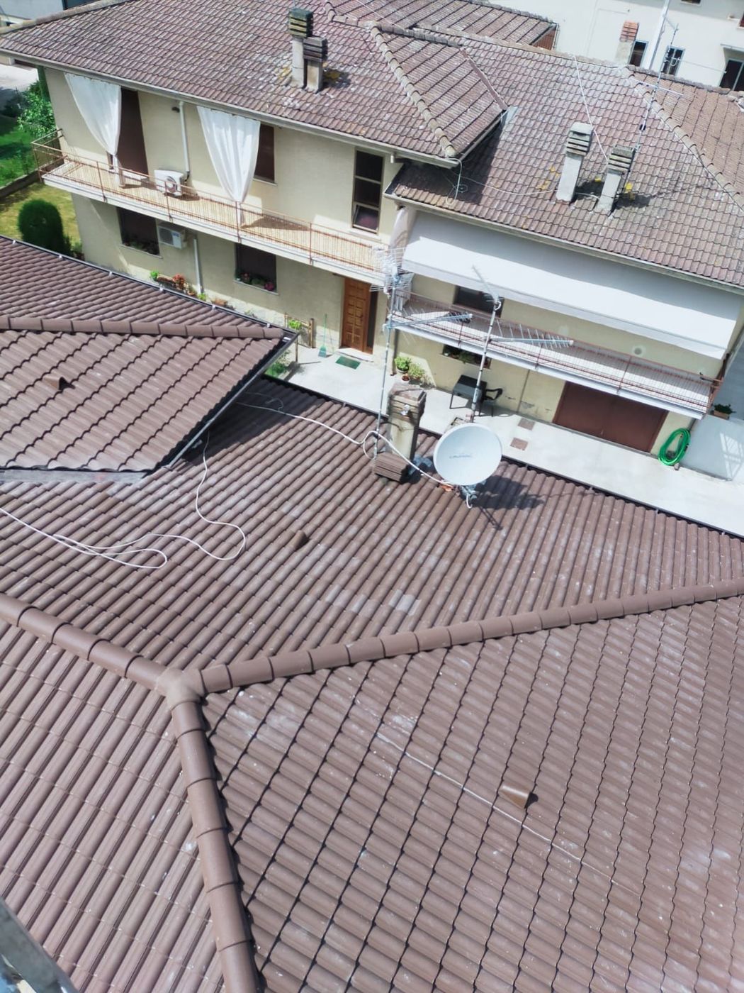 Veduta aerea dei tetti di tegole degli appartamenti, con balconi e parabola satellitare, in un complesso residenziale.