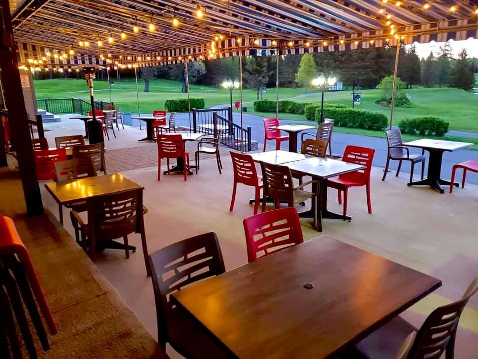 Un patio avec tables et chaises sous un auvent.