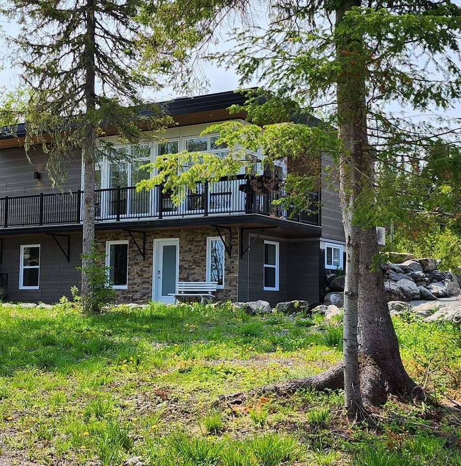 Une grande maison avec un balcon est entourée d'arbres et d'herbe.