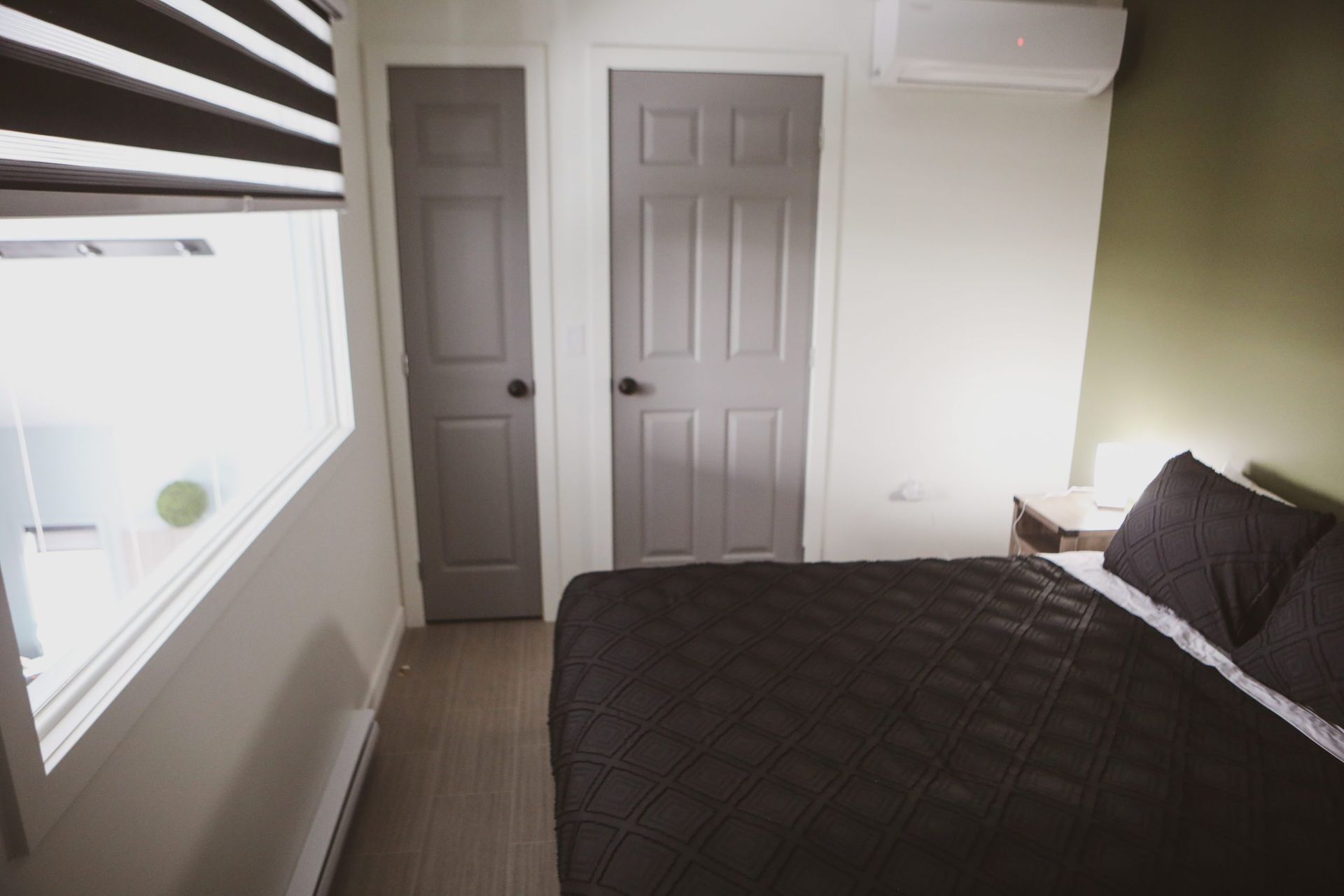 Une chambre avec un lit, deux portes et une fenêtre.