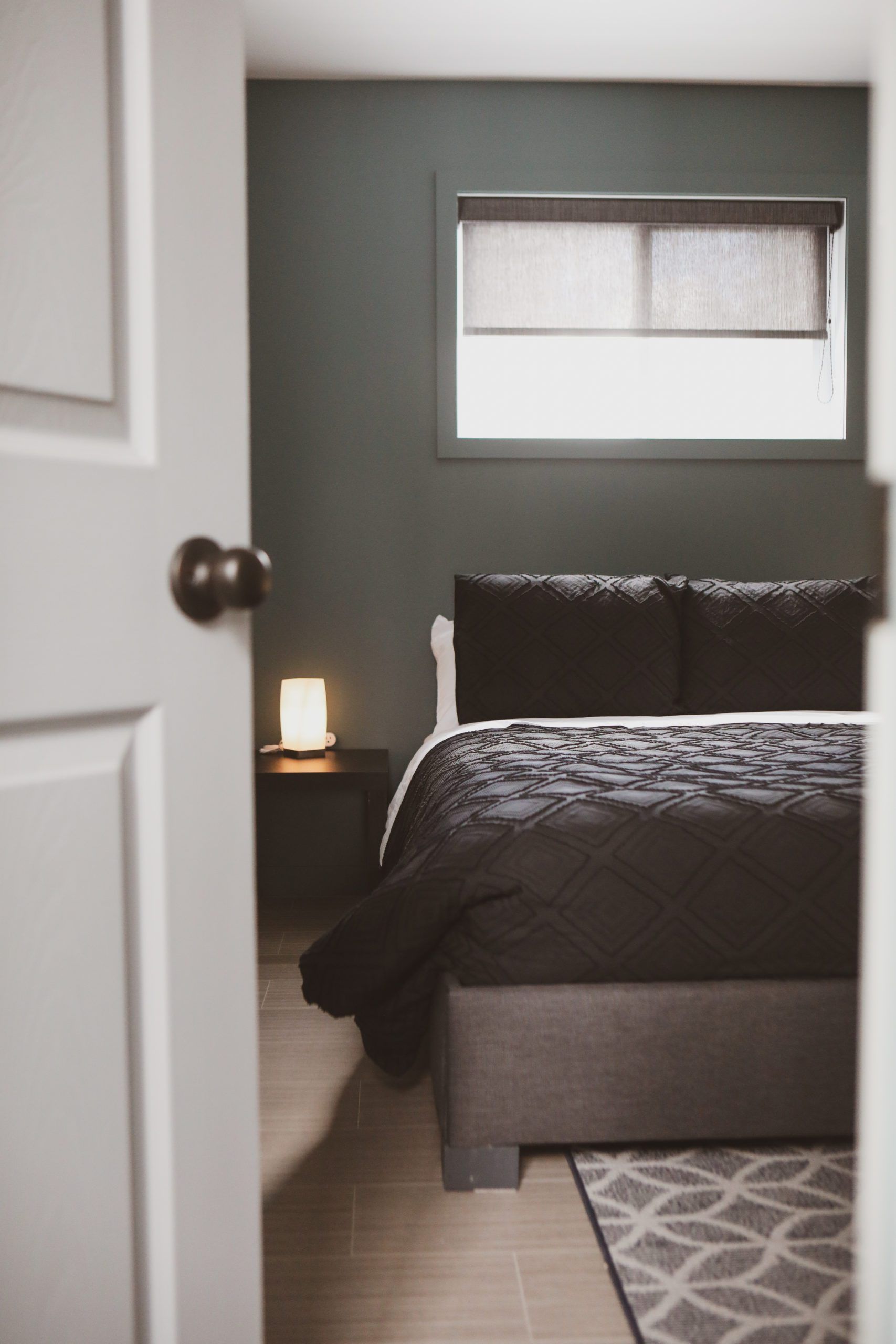 La porte est ouverte sur une chambre avec un lit et une fenêtre.