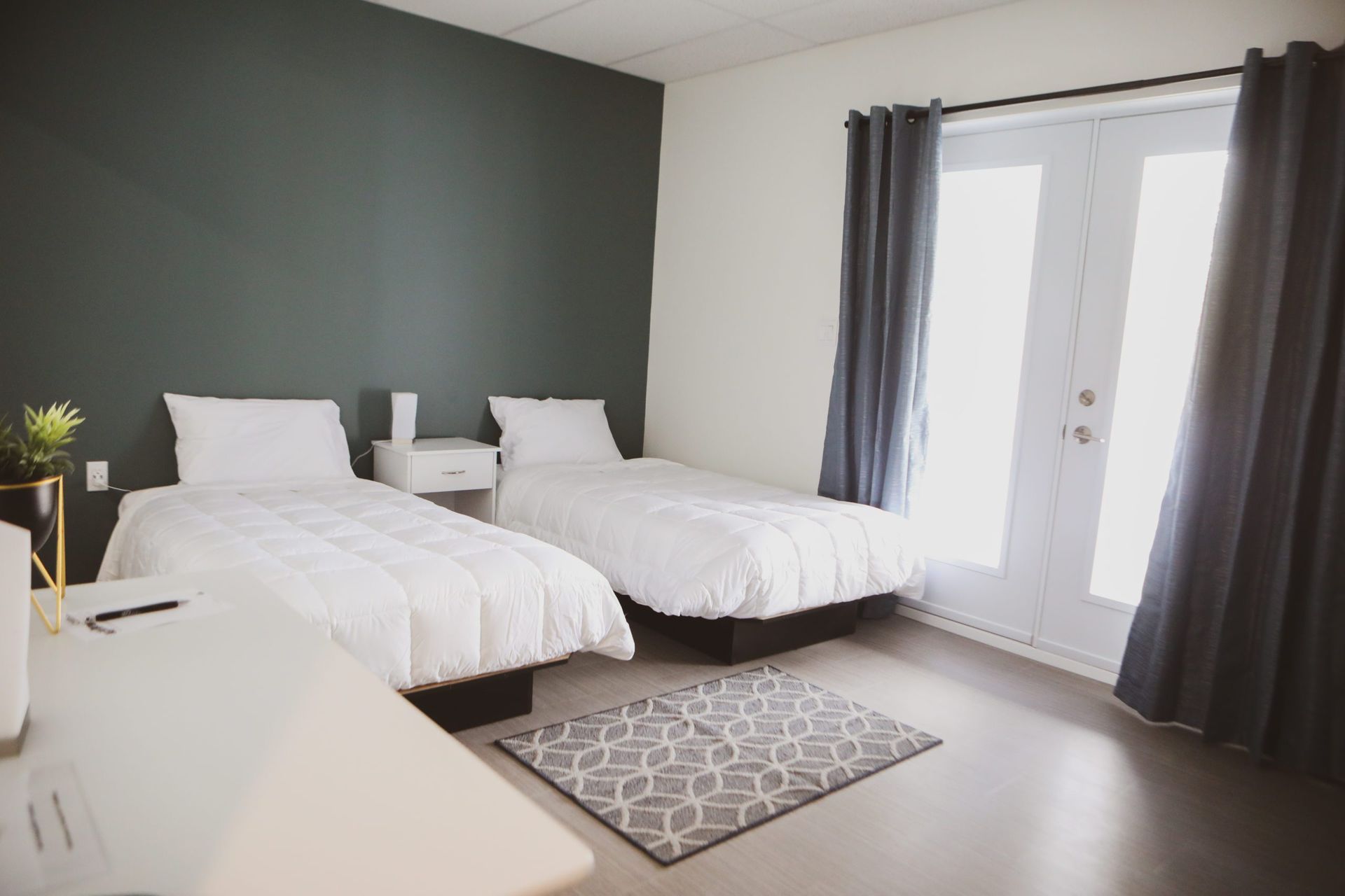 Une chambre avec deux lits, un tapis et une fenêtre.