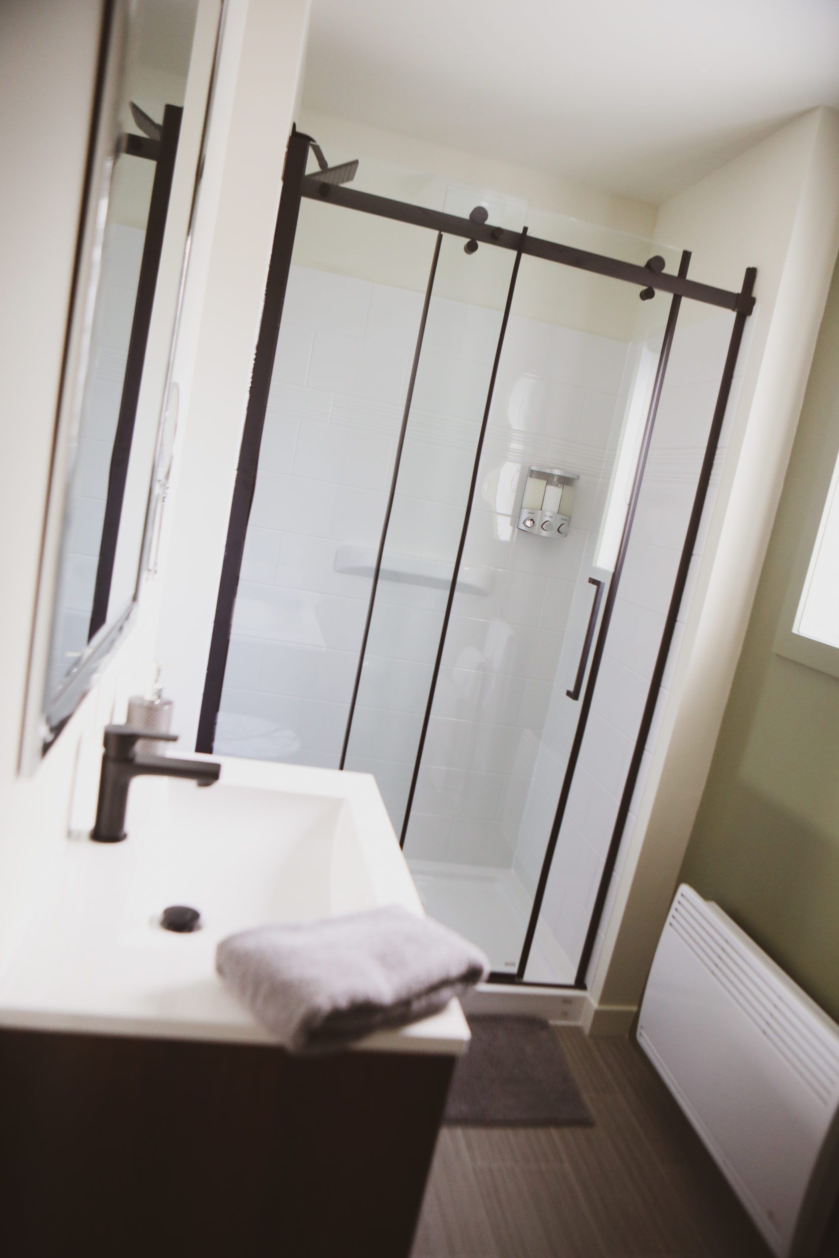 Une salle de bain avec un lavabo et une douche avec portes coulissantes en verre.