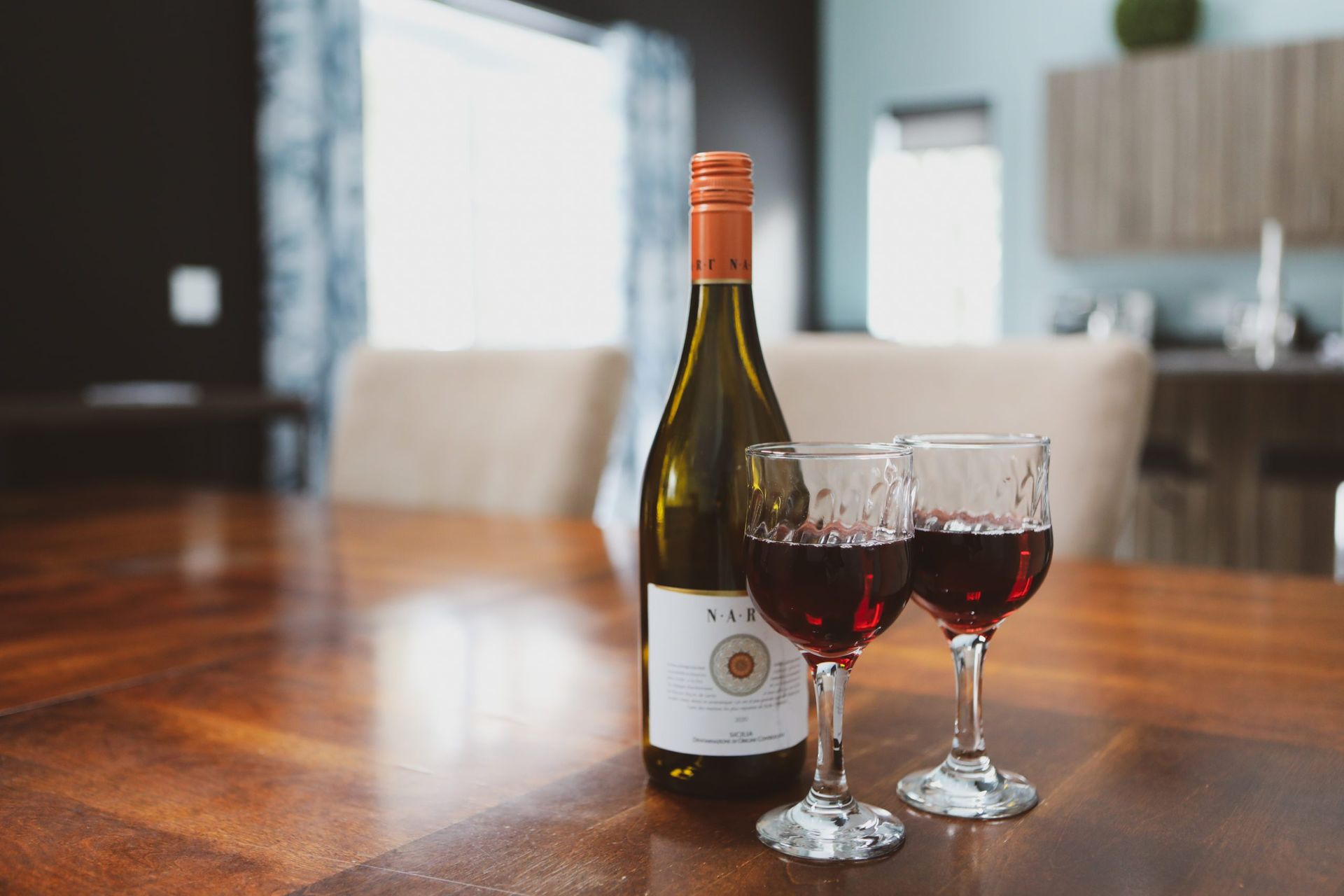 Une bouteille de vin et deux verres de vin sont sur une table en bois.