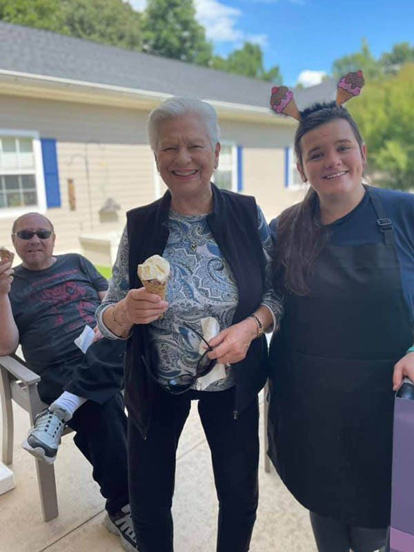 A woman is holding an ice cream cone while standing next to two other people.