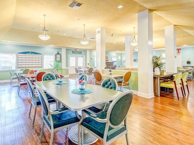 A large dining room with tables and chairs in a nursing home.