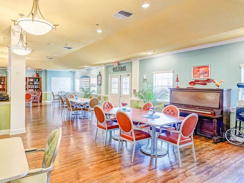 A large dining room with tables and chairs and a piano.