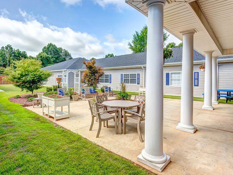 There is a patio with tables and chairs in front of a house.