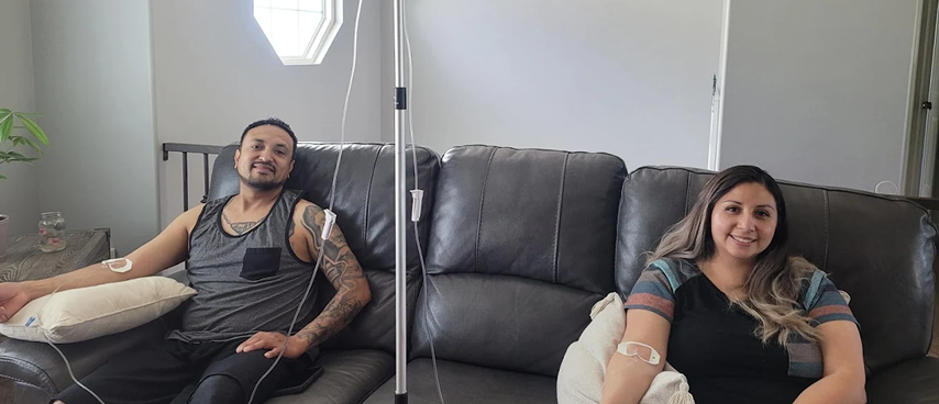 Couple receiving in-home IV drip therapy on living room sofa