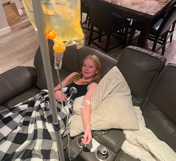Young woman resting on couch while receiving IV drip therapy at home