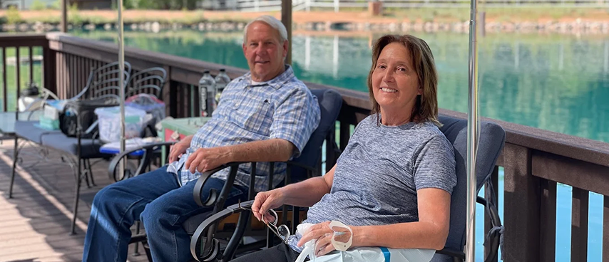 Older couple relaxing outdoors on patio while receiving mobile IV therapy