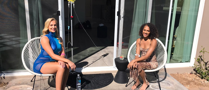 Two women sitting outdoors receiving IV drip therapy