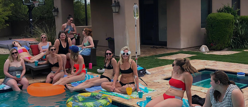 Group of women relaxing poolside receiving IV therapy