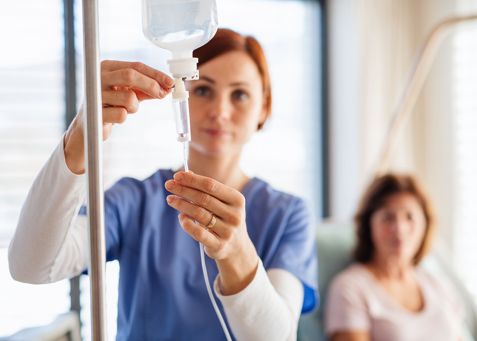 Nurse adjusting IV drip bag for patient during mobile IV therapy session