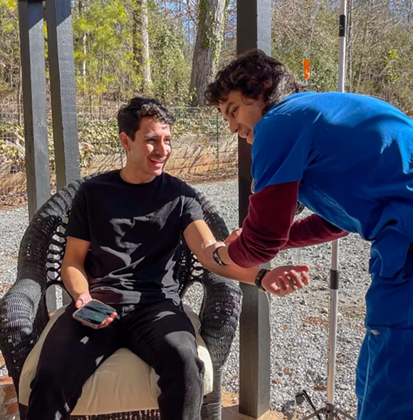 Healthcare provider administering IV therapy to patient outdoors