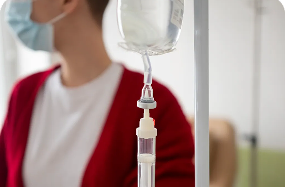 Close-up of IV drip bag with patient in background