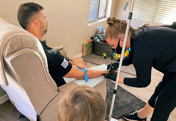 Healthcare provider administering IV therapy to patient at home