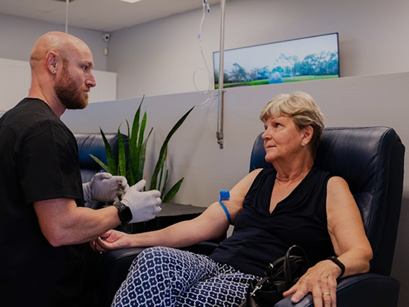 A woman is sitting in a chair getting an injection from a doctor.