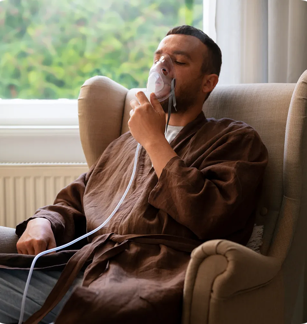 A man wearing an oxygen mask is sitting in a chair