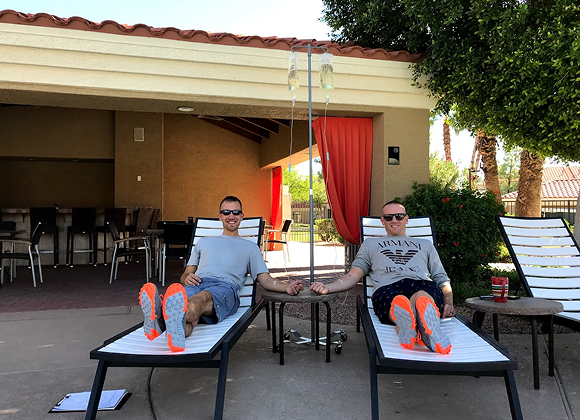 Two men are sitting on lounge chairs in front of a building.