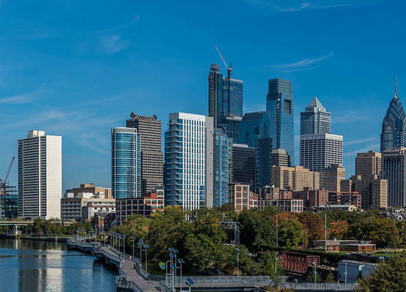 A city skyline with a bridge in the foreground and a river in the background.