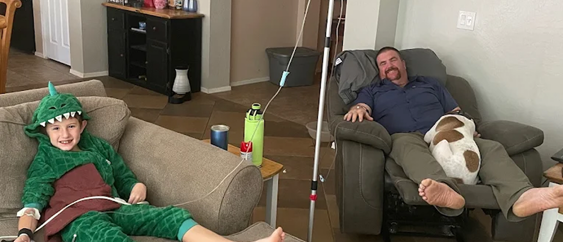 Man and child in dinosaur costume receiving IV drip therapy at home