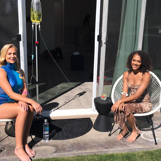 Two women are sitting on a patio in front of a sliding glass door