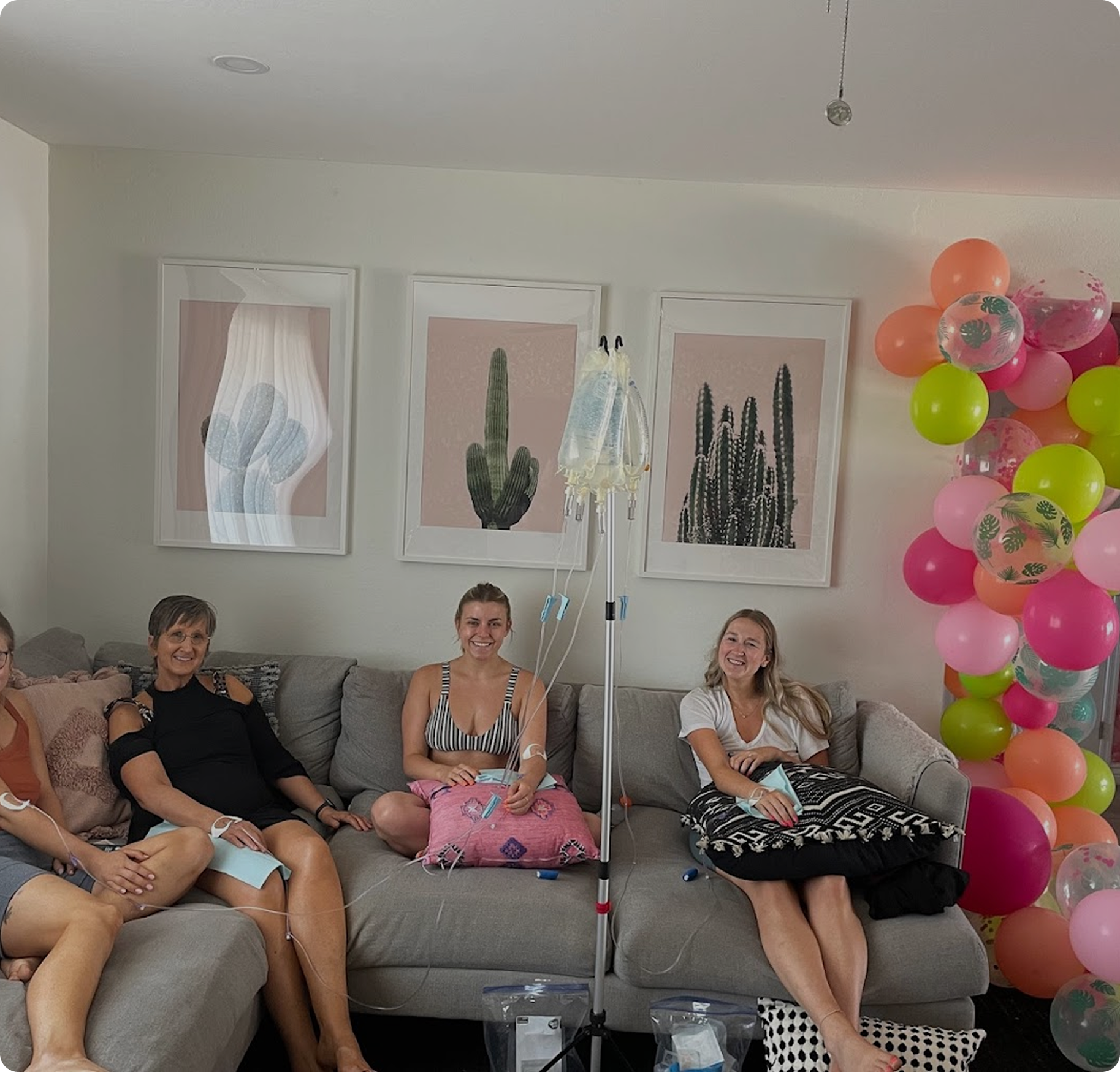 A group of people are sitting on a couch with balloons in the background