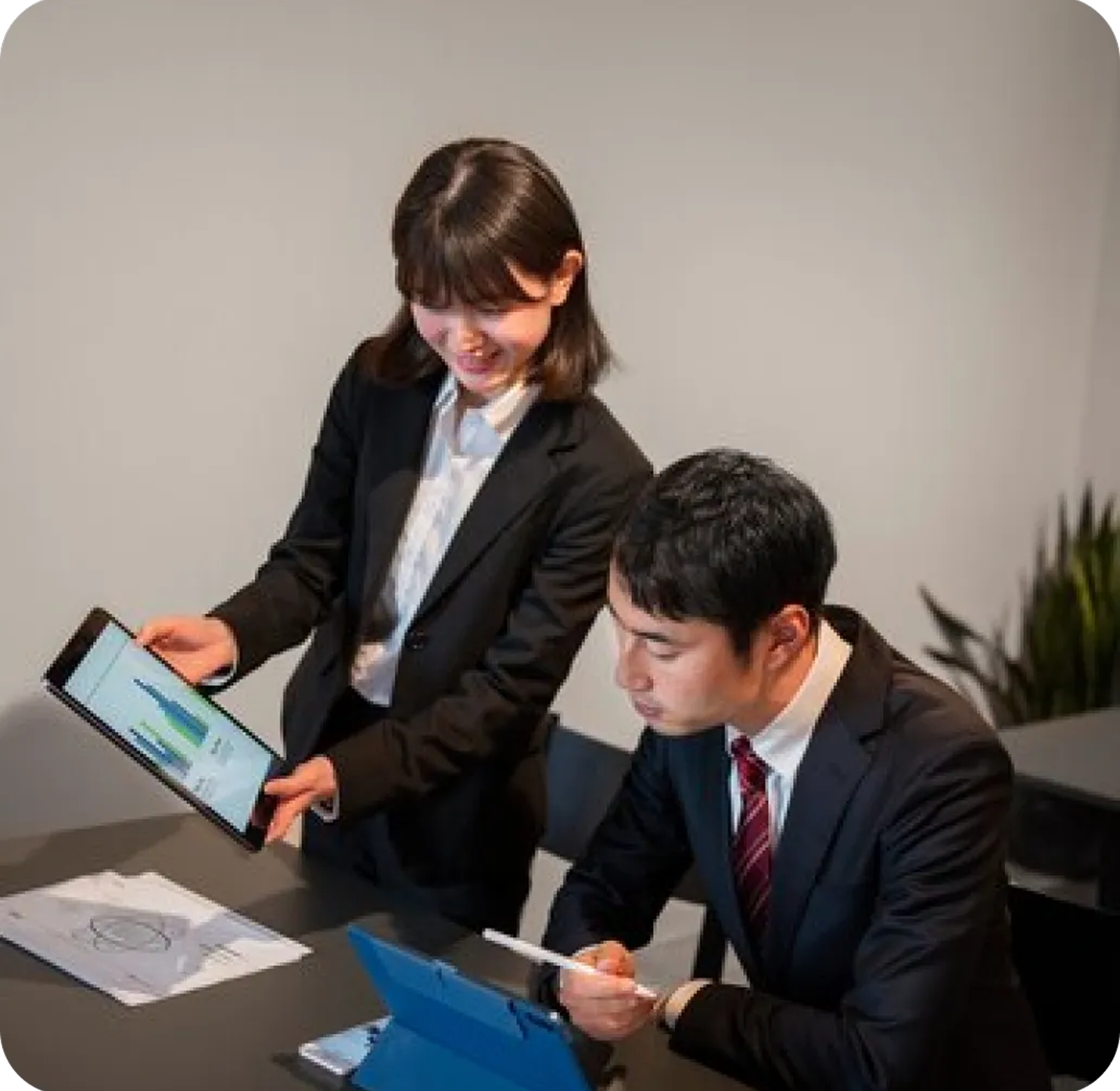 A man and a woman are sitting at a table looking at a tablet.