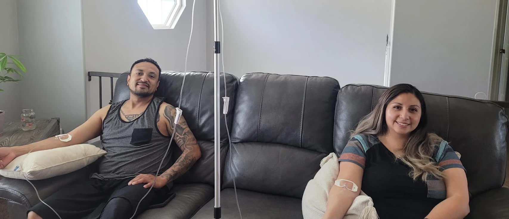 Couple receiving in-home IV drip therapy on living room sofa