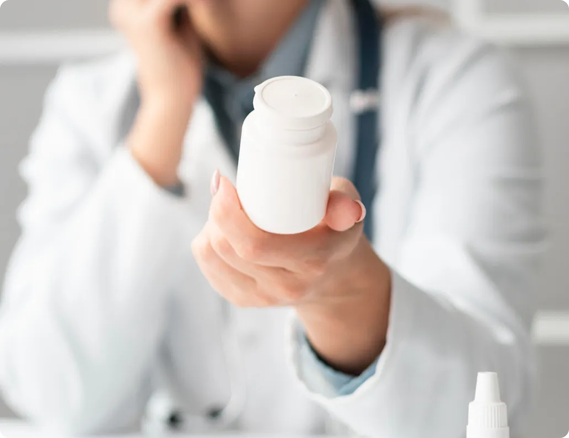 A doctor is holding a bottle of pills in his hand.
